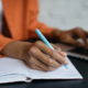 Simulated Workplace article image: depicts a student working on a computer and taking notes by hand