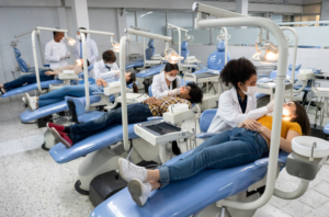 Dental students practice on patients in their dental chairs.