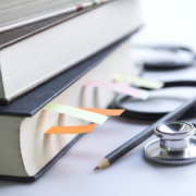 Medical student textbooks with pencil and multicolor bookmarks and stethoscope isolated on white